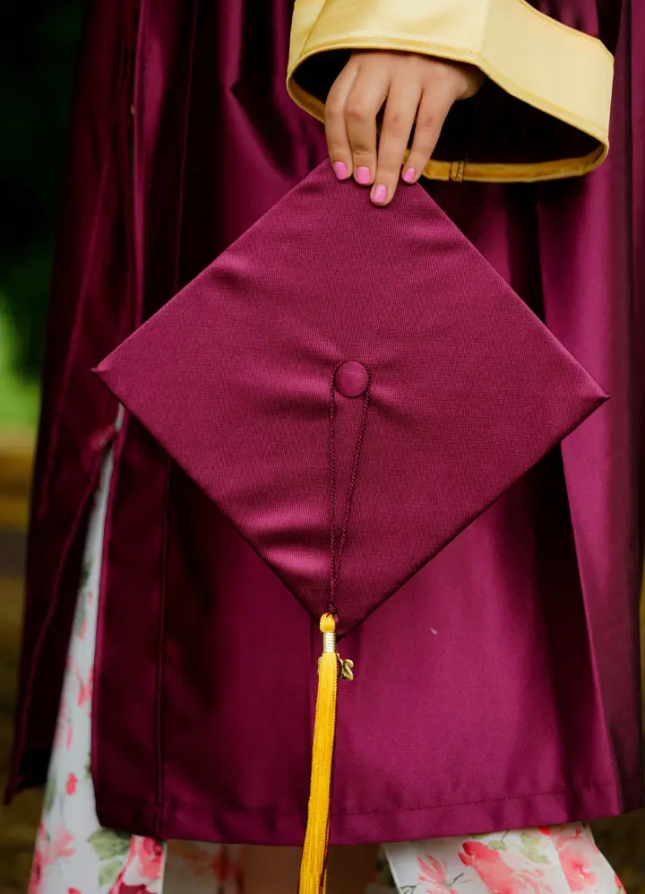 A student holds their graduation cap